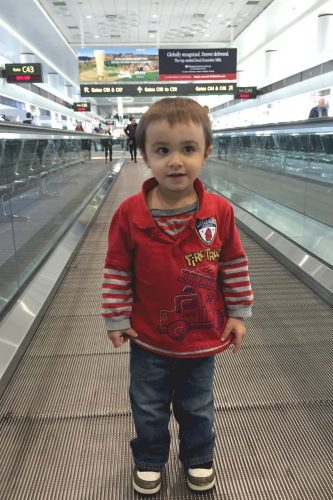 Toddler riding conveyor belt in airport